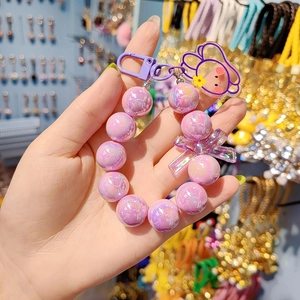 Charming purple beaded keychain with a bow and bear pendant shown in a hand-held view