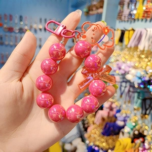 Pink beaded phone charm with a cute cartoon bear and bowknot pendant details