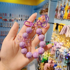 Detailed view of purple beaded phone charm with transparent bow and cute bear acrylic pendant