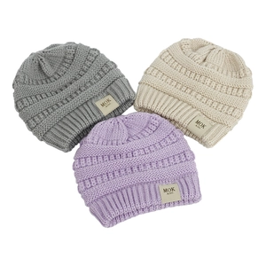 Close-up of thick knitted baby hats in grey, beige, and lilac with MOK labels