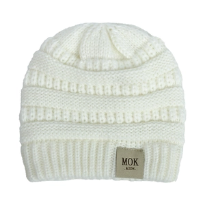 Detail of soft white cable knit texture and MOK leather tag on baby winter beanie