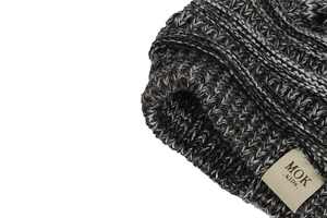 Close-up of baby knit hat showing brown mixed yarn texture and MOK KIDS cloth label