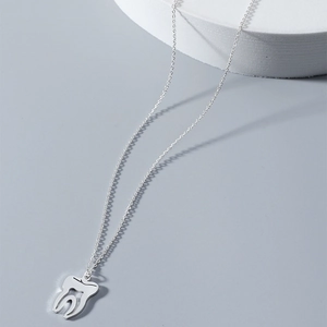 Détail macro du pendentif dent molaire évidé en acier argenté sur une chaîne fine