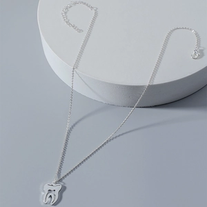 Gros plan du pendentif dent creux argenté avec sa fine chaîne ajustable en métal