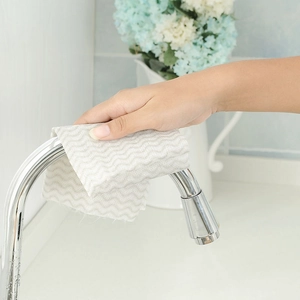 Absorbent disposable kitchen cleaning cloth cleaning a metal faucet in home setting