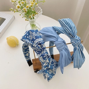 Close-up of three fabric headbands in blue floral, denim, and striped patterns on a desk