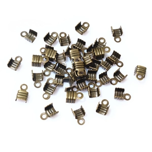 Macro view of antique bronze DIY metal cord end crimps and jewelry findings on white surface