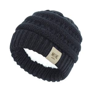 Close-up of black knit baby beanie showing warm fleece lining and leather brand label