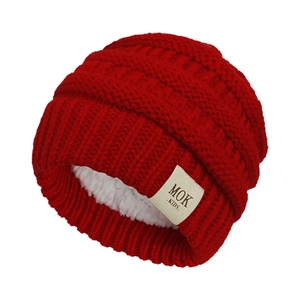 Detail of red cable knit baby hat with warm white fleece lining and MOK KIDS logo