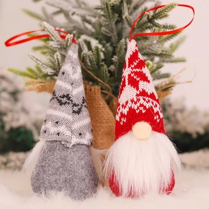 Charming red and grey knitted Christmas gnomes hanging on a festive decorated tree