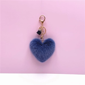 Detailed view of dusty blue plush heart keychain with gold hardware and black silk tassel