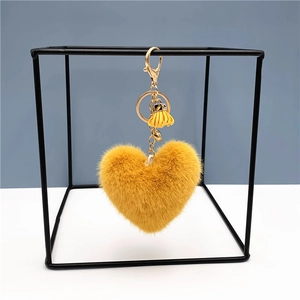 Detail of yellow plush heart keychain with gold hardware and a small leather tassel