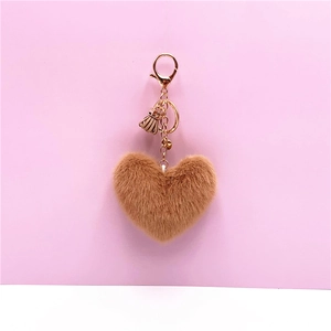 Close-up of brown heart plush keychain with golden metal hook and elegant tassel detail