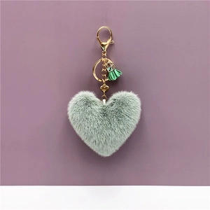 Macro shot of mint green plush heart keychain with gold hardware and small tassel detail
