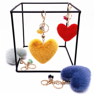 Colorful plush heart keychains with tassels hanging on a modern minimalist display rack