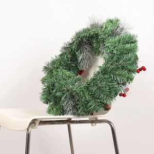 Christmas wreath with snowy pine needles, red berries and pinecones on white chair