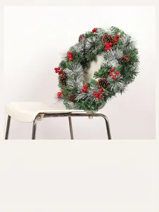 Close-up of pine needles with white frost and red berries on a Christmas wreath