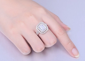 Close-up of S925 silver ring featuring an emerald cut central gem and halo setting