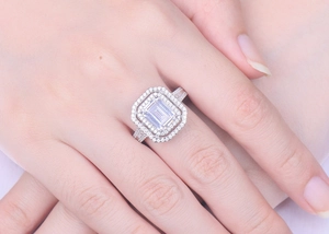 Macro view of emerald cut faux diamond ring with double halo and pavé band