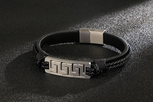 Detail of multi-layer braided leather bracelet with Greek key pattern on steel buckle