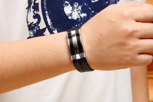 Detail of hand-woven black leather multilayer men's bracelet with a two-tone steel clasp