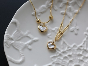 Detailed close-up of heart-shaped white mother of pearl pendants on 18K gold plated chains
