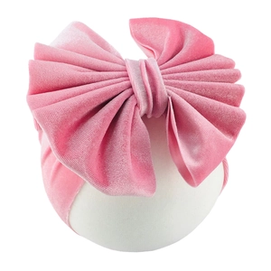 Close-up of pink velvet baby headband with a large handmade bow and soft texture