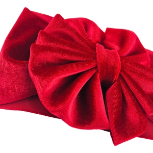 Macro shot of large red velvet bow headband showing soft fabric texture and glossy finish