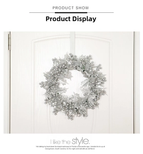 Couronne de Noël argentée avec feuilles métalliques et baies sur une porte blanche