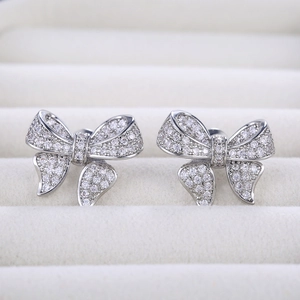 Macro view of silver bow-shaped earrings with pave-set white cubic zirconia stones