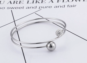 Macro detail of double-layer silver bangle featuring a crystal-studded sphere end