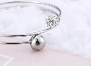 Detail of silver double-layered steel cuff with a crystal-studded sphere and metal ball