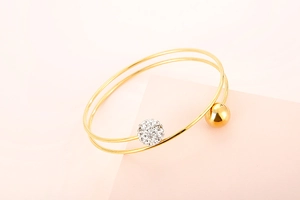 Close-up of double-layer gold titanium bracelet featuring a sparkling rhinestone-set ball