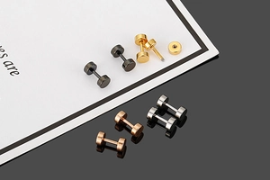 Macro detail of screw-back dumbbell earrings in black gold silver and rose gold finishes
