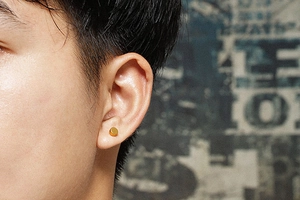 Close-up of a minimalist gold round barbell stud earring worn on the earlobe