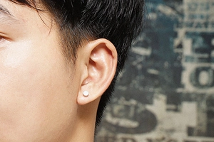 Close-up of a minimalist silver round stud earring worn on the earlobe for a modern look