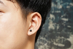 Close-up of a black matte screw-back barbell stud earring worn on the earlobe
