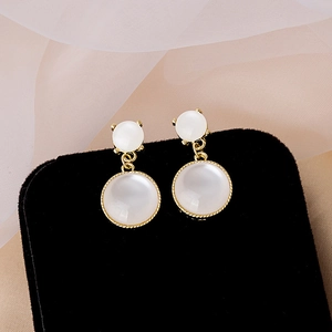 Elegant gold-tone drop earrings with white cat eye stones on black velvet and satin base