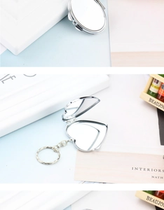 Macro detail of a heart-shaped silver metal folding mirror keychain with polished finish