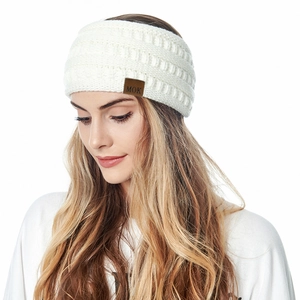 Detail view of a white fleece-lined knit headband with a brown leather MOK label for women