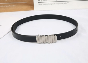 Detail of slim black belt with unique silver ribbed snap buckle on textured background