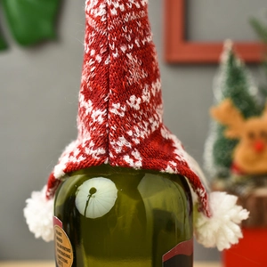 Red knitted Christmas wine bottle cover with snowflake pattern and white pompom decor