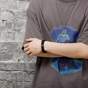 Men's leather bracelet with cross pendant and beaded strand shown on a male model