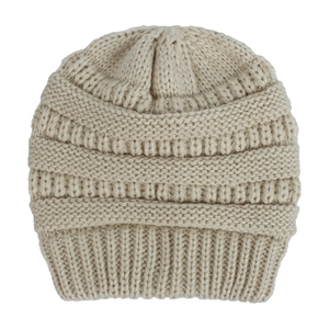 Dettaglio del cappello neonato beige lavorato a maglia con trama spessa e motivi a costine