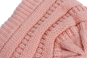 Dettaglio ravvicinato del cappello in maglia per neonati con trama a treccia rosa