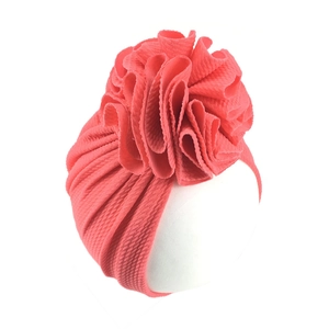 Detail of coral waffle knit baby turban hat featuring a large layered sunflower design