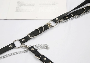 Detail of gothic leather body harness with silver metal rings and heart-shaped chains