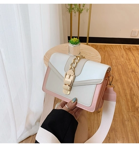 Detailed shot of white and pink crossbody bag with wide canvas strap and gold chain