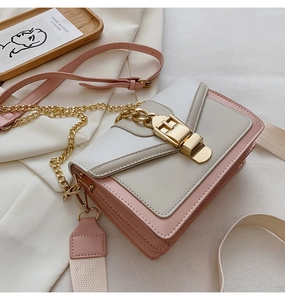 Detail view of contrast color crossbody bag with gold lock buckle and dual straps