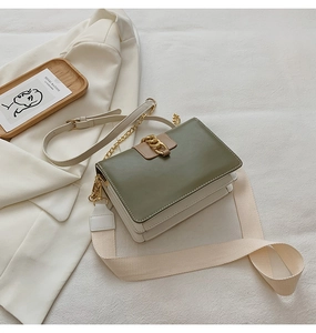 Detail of color-block olive green and cream crossbody bag with gold chain lock detail